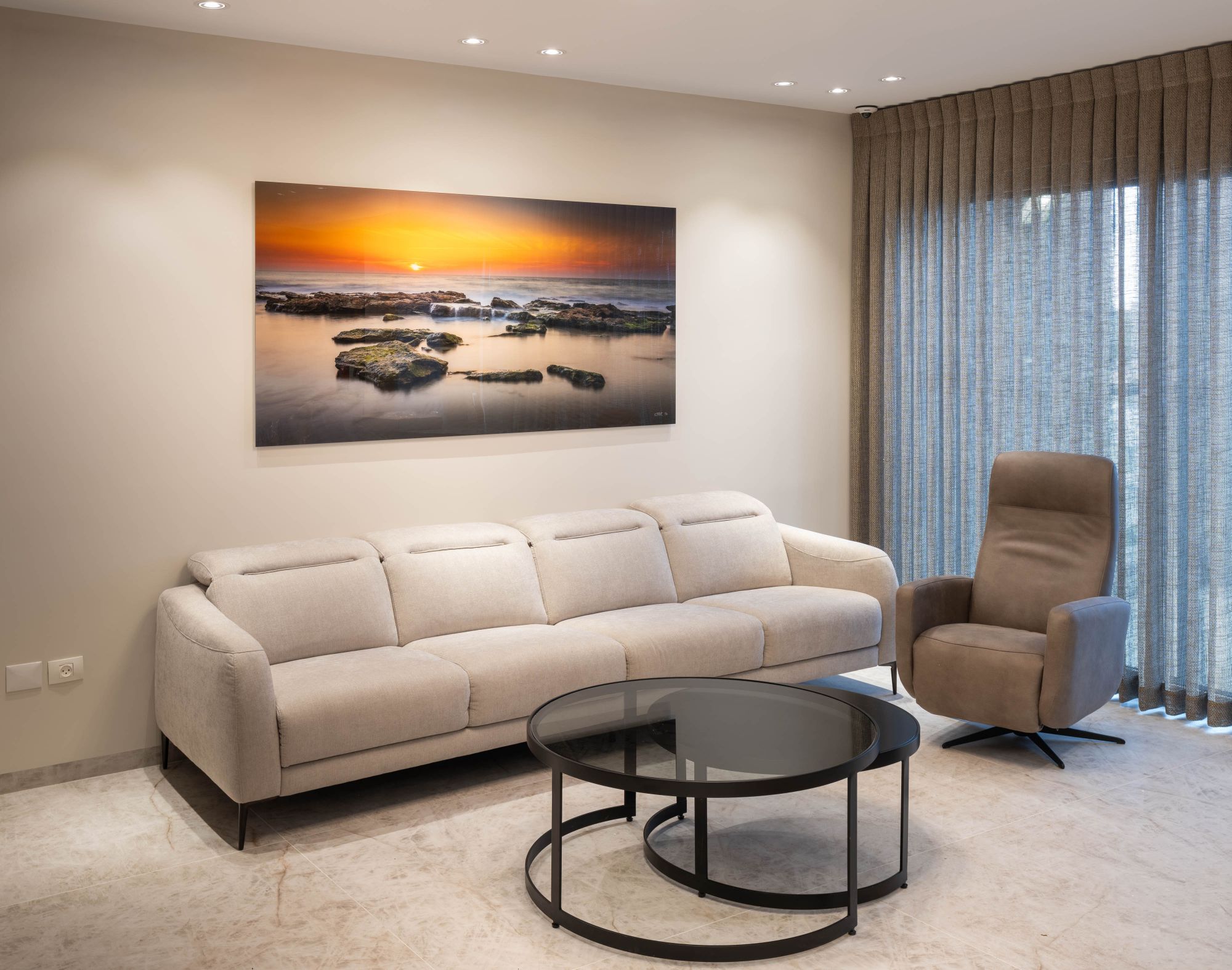 A coastal sunset piece above a living room sofa
